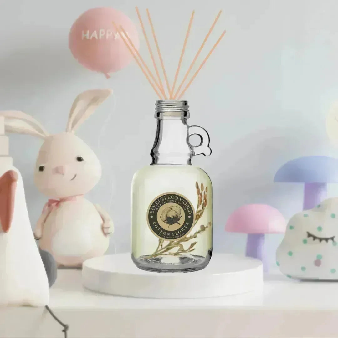 Cotton Flower room freshener bottle with bamboo sticks on a white stand beside pastel nursery toys