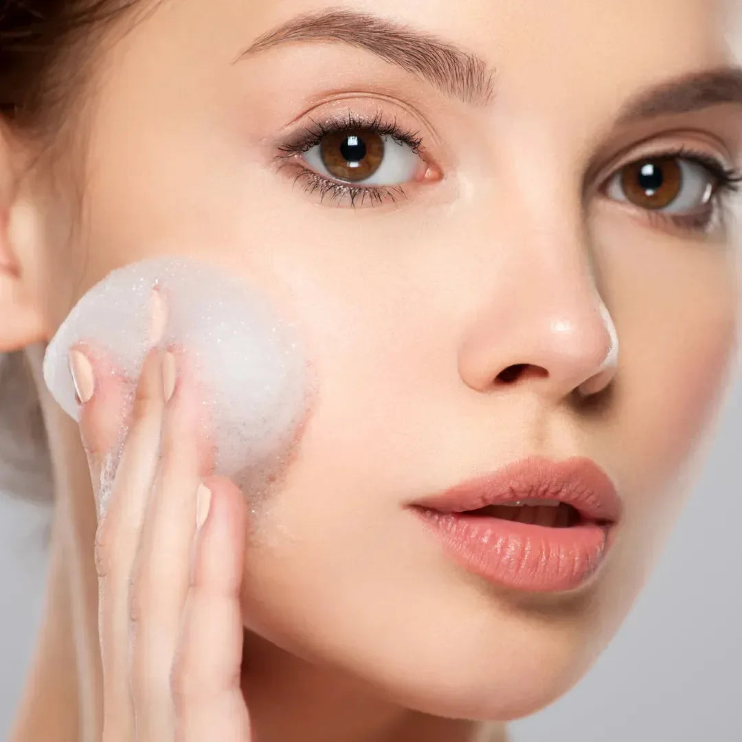 A woman washing her cheek with a lathered konjac sponge