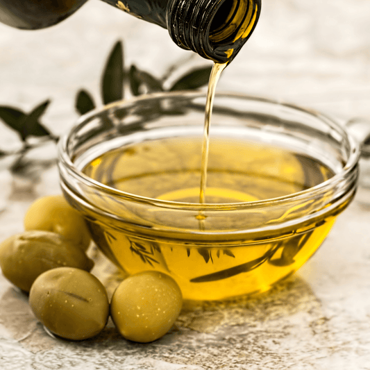 Olive oil pouring into a glass bowl with fresh olives, ideal for skincare by WEDOART-IL.