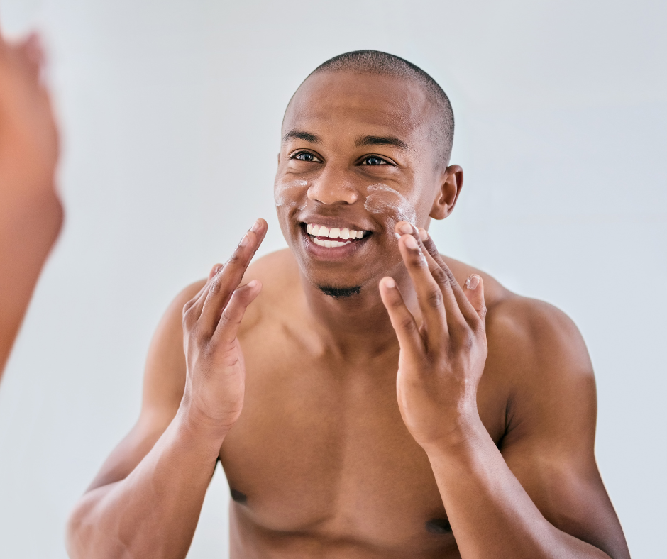 Smiling man applying facial cream during his skincare routine, promoting healthy skin care.