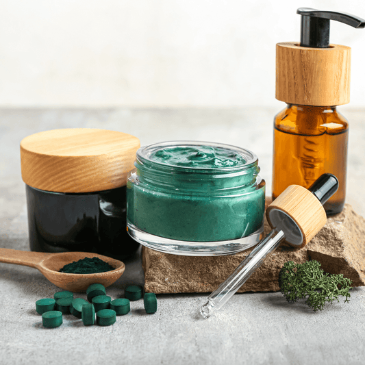 Spirulina skincare creams, serum, and tablets on stone with green powder, natural cosmetic products