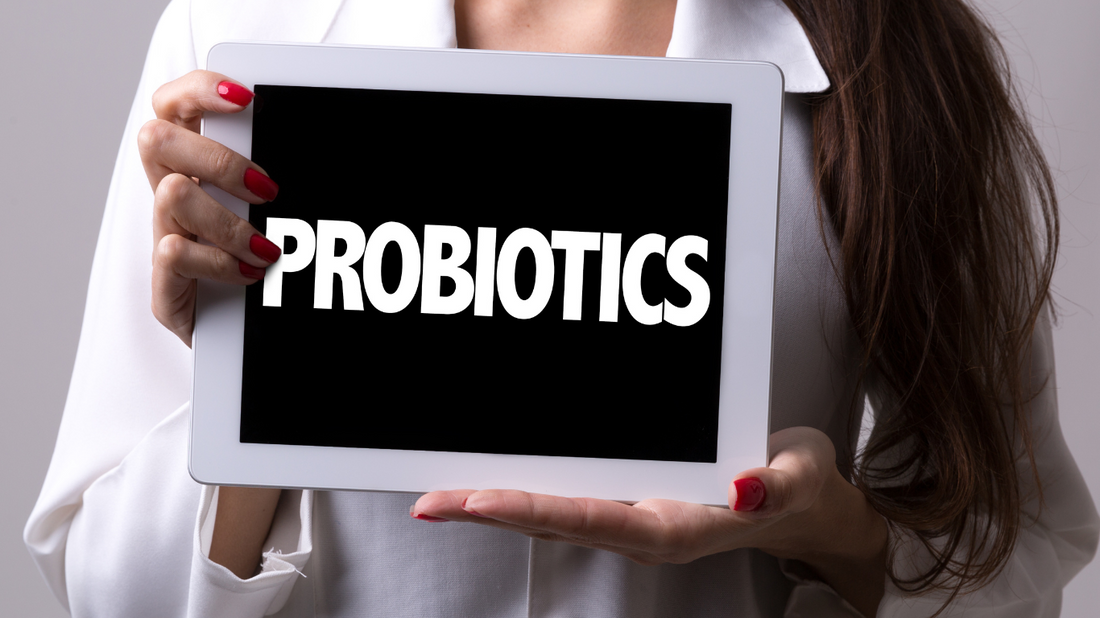 Woman holding tablet displaying 'Probiotics' text, promoting skincare and wellness.