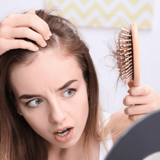 Worried woman checking hair loss in mirror with hairbrush full of hair, WEDOART-IL skincare context
