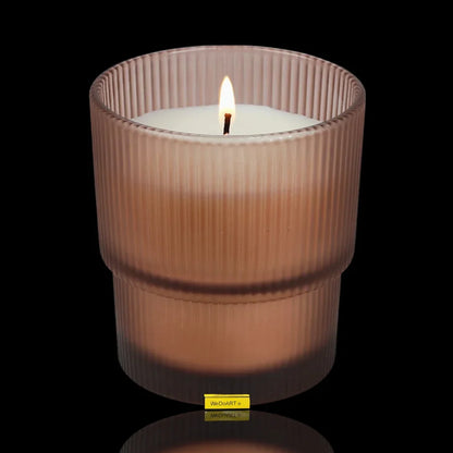 Lit scented candle in a ribbed frosted glass jar against a black background