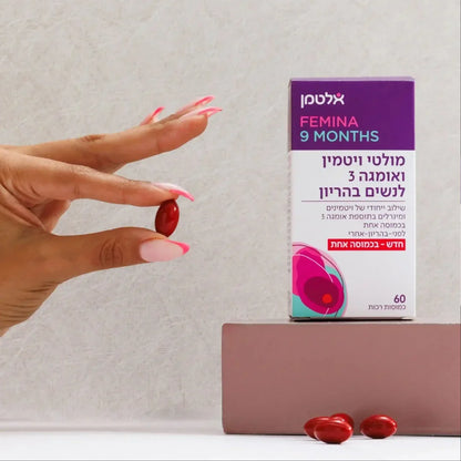 Hand holding a red omega-3 softgel next to Femina 9 Months prenatal multivitamin box.
