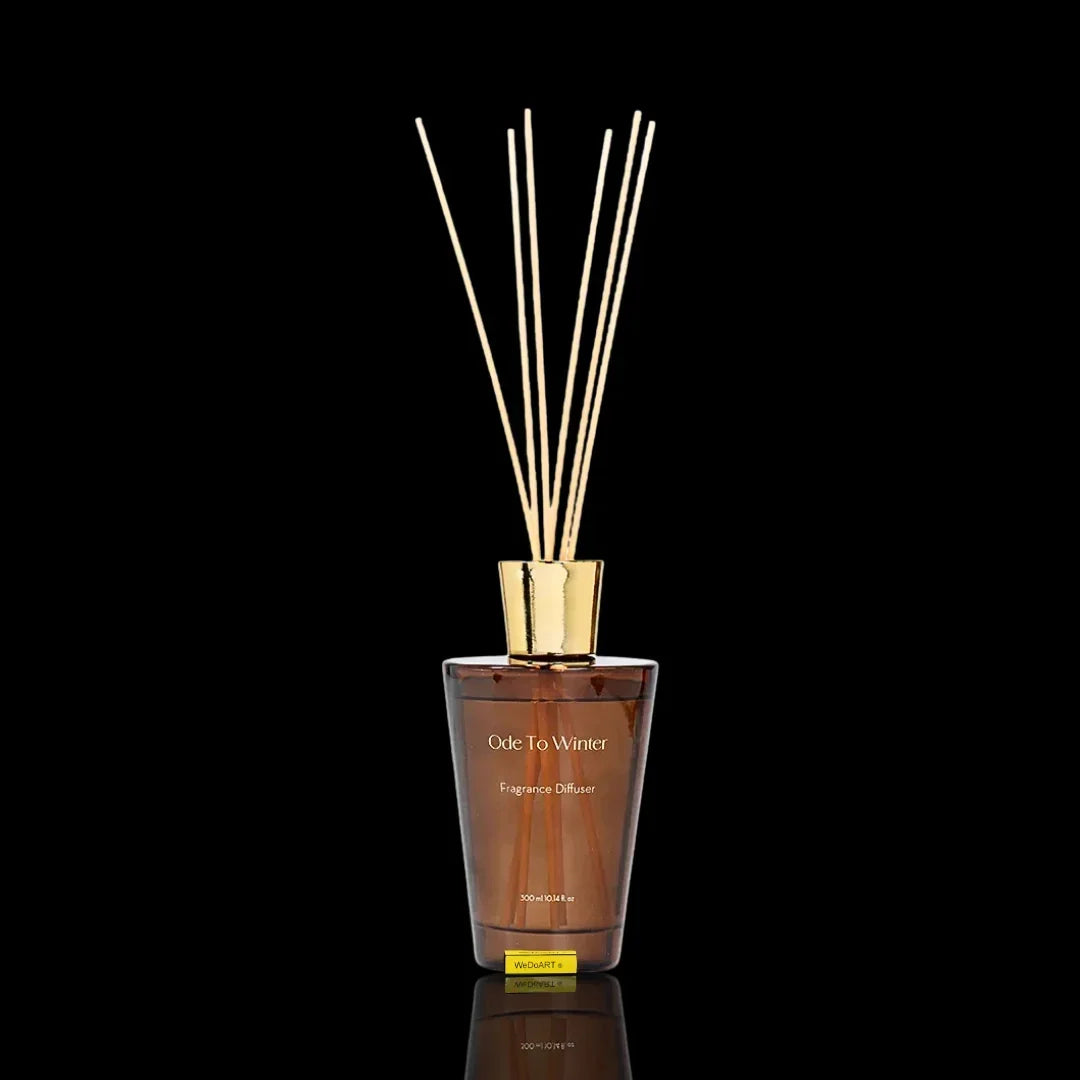 Ode To Winter fragrance diffuser in a brown glass bottle with gold reeds on a black background