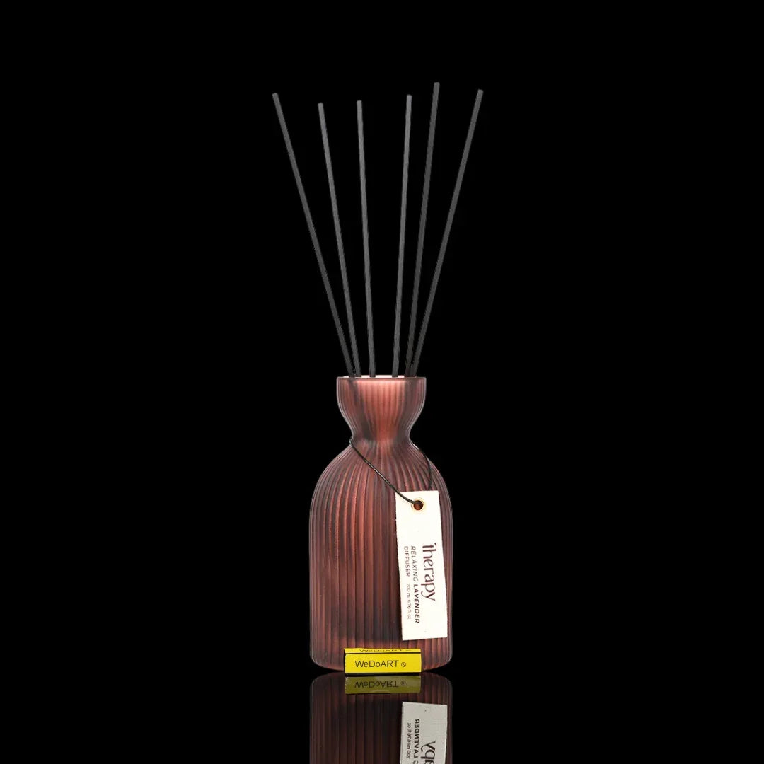 Red ribbed glass reed diffuser with black sticks and Therapy Lavender tag on black background
