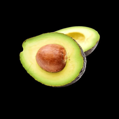 Halved ripe avocado showing its green flesh and brown stone on a black background