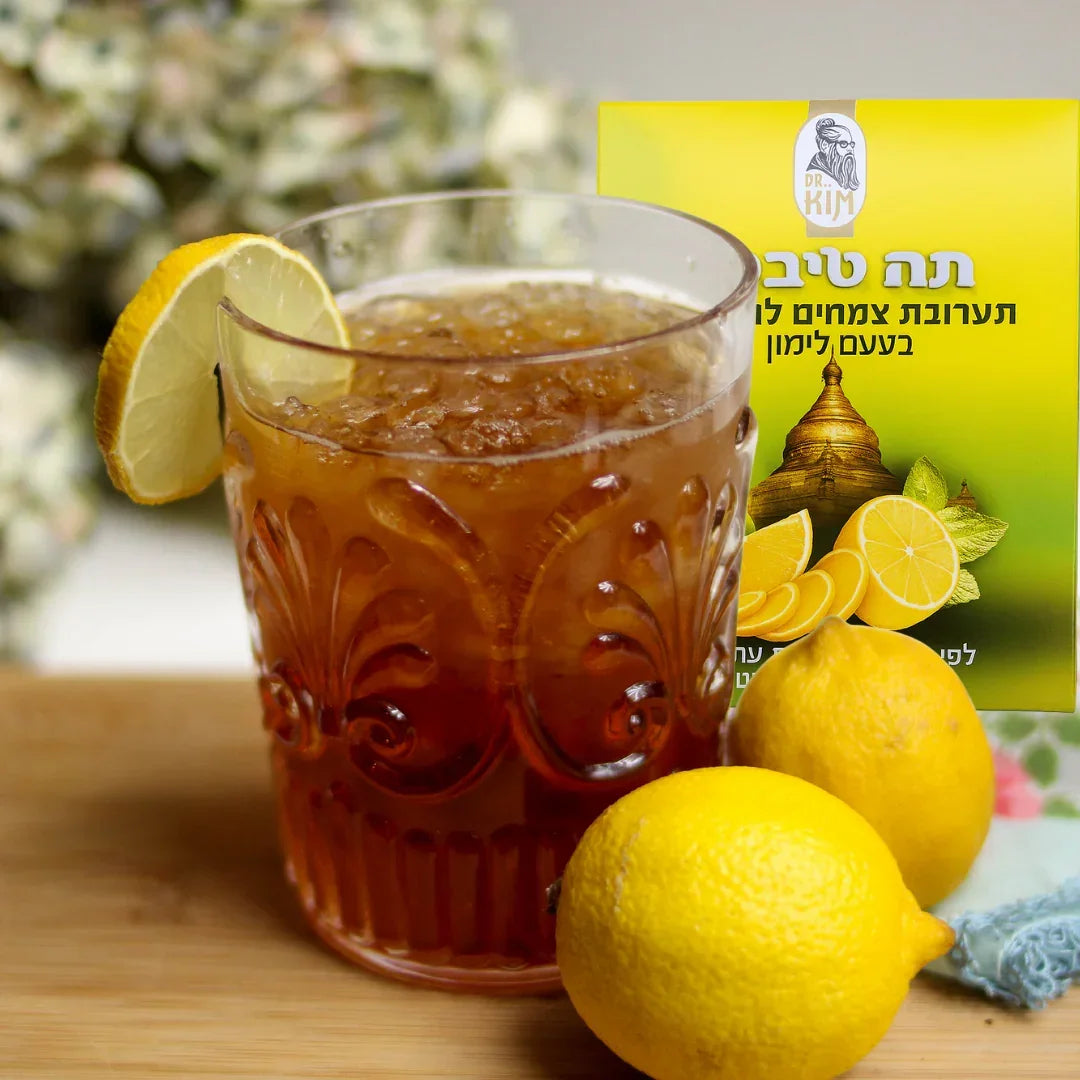 Glass of iced Lemon Tibetan Tea with a lemon wedge beside the Dr. Kim 180 g box and fresh lemons