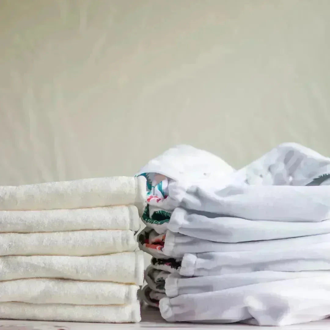 Stacks of folded white towels and cloth diapers on a shelf