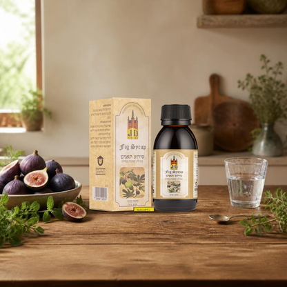 J.D. Schloss Fig Syrup 100 ml bottle and box on a wooden kitchen counter with fresh figs and a glass of water