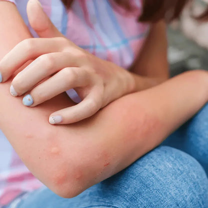 Child resting one hand on a forearm while sitting outdoors