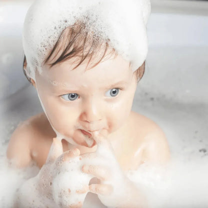 Baby with soft shampoo foam on the hair during bath time