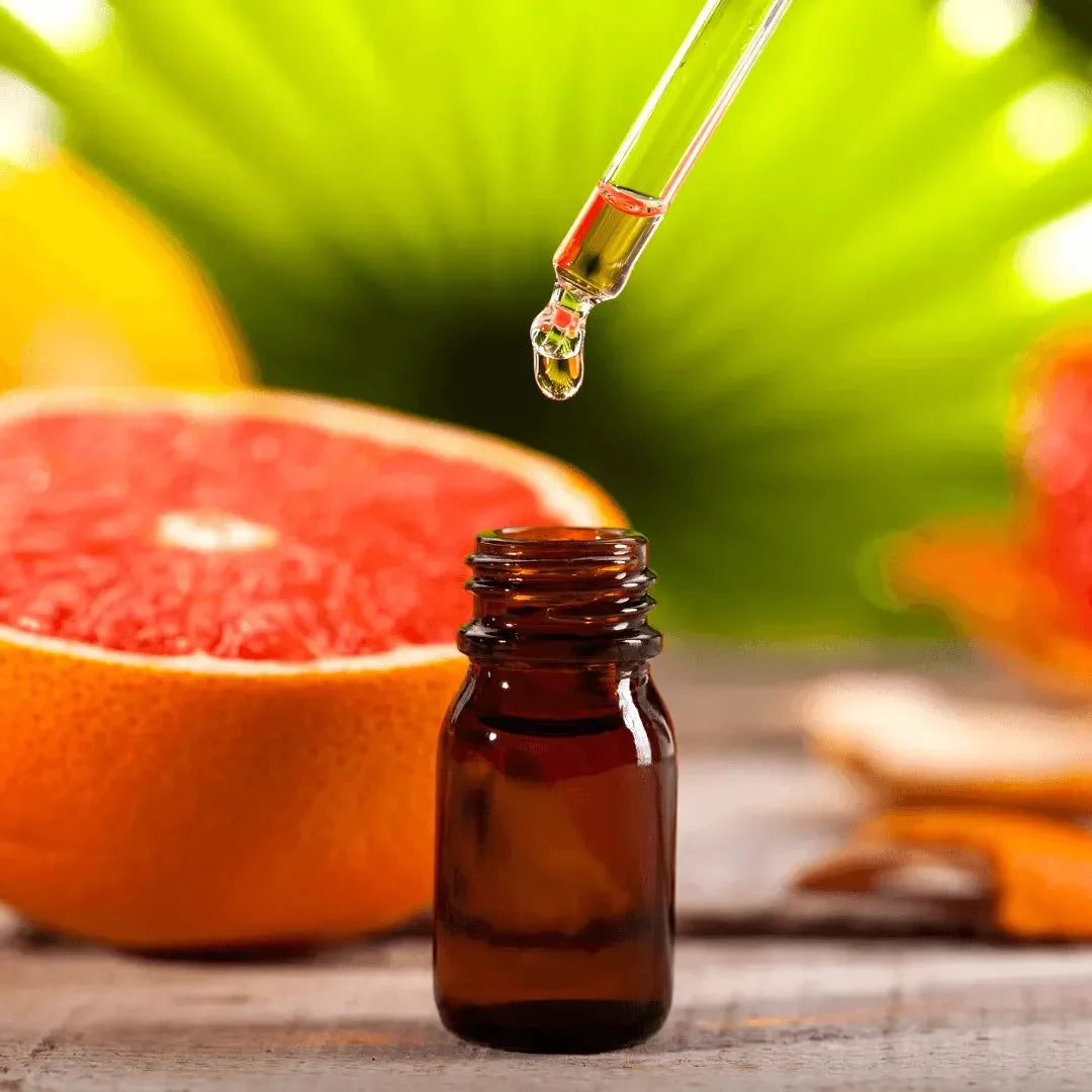 Dropper bottle beside a halved pink grapefruit and a bright green leaf