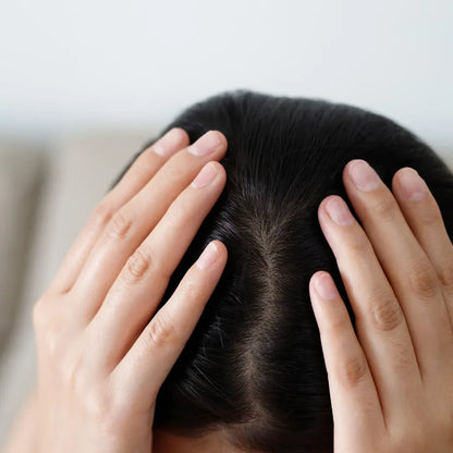 Hands resting on the top of a woman's head, showing her hair parting