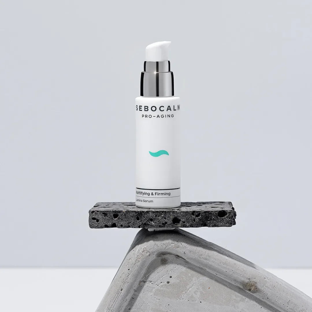 SeboCalm Pro-Aging Lumina serum bottle standing on a dark stone block against a pale grey background