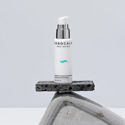 SeboCalm Pro-Aging Lumina serum bottle standing on a dark stone block against a pale grey background