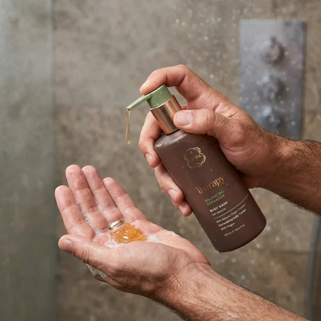 A person dispensing Therapy Balancing Body Wash into their palm in a shower.